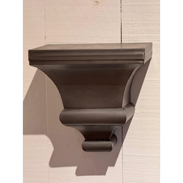 Pair of metal wall brackets with molded shelf tops over tapered, stepped bodies in a soft pewter gray finish. Priced for...