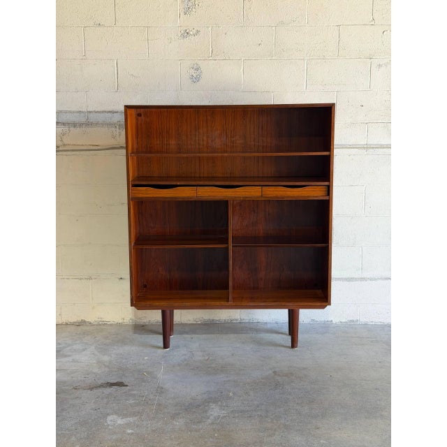 This architectural open shelving unit features an elegant upper display area paired with deep lower cubby storage modules....