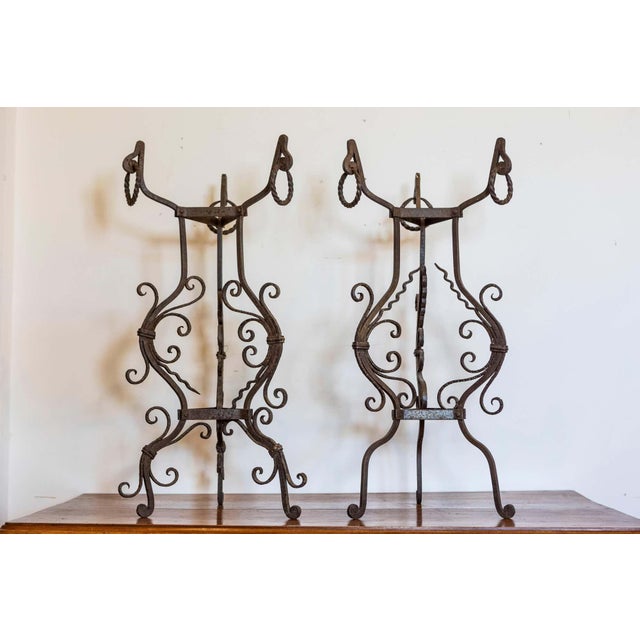 A pair of Italian hand-made wrought-iron plant stands on tripod bases from circa 1900 with scrolling accents. This...
