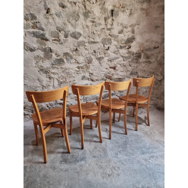 Set of four original French bistro chairs dating from the 1960s. The chairs feature solid beech frames with molded plywood...