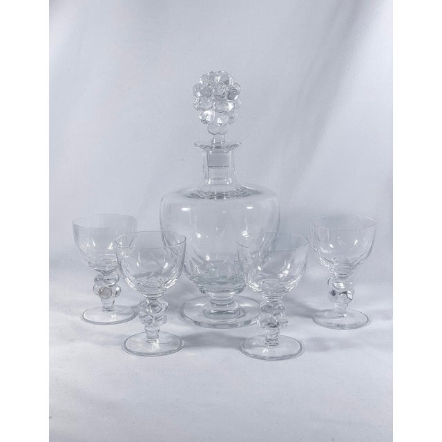 Lalique Crystal "Clos Vougeot" Decanter and Tasting Glass Set Decanter with four glasses, tulip-shaped bowls. Each item is...