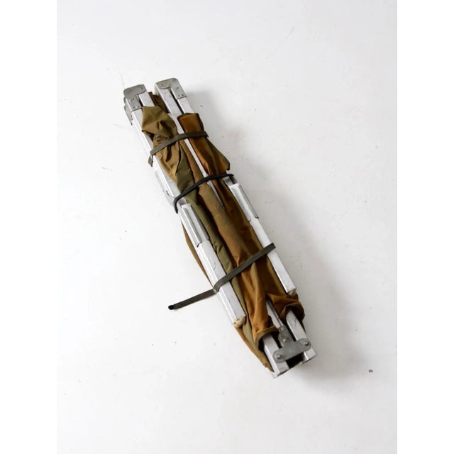 This is a vintage cot. The folding cot features a metal x-frame with end bars and a green nylon canvas top. Bed Width: 27"