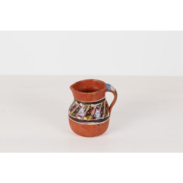 Add earthy warmth and rustic folk-art charm to your interior with this small vintage Mexican terracotta pitcher, featuring...