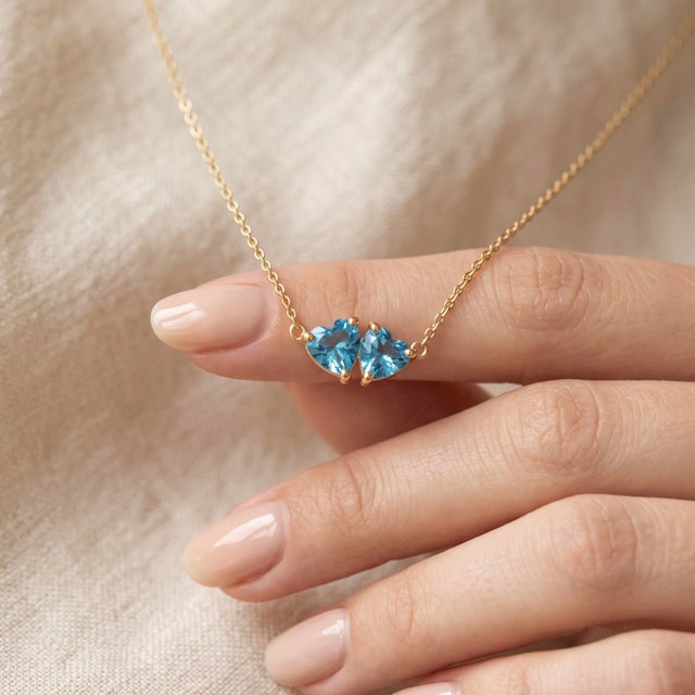 Cool down your style with this serene two-stone pendant necklace, featuring two sparkling sky-blue heart-shaped gemstones...