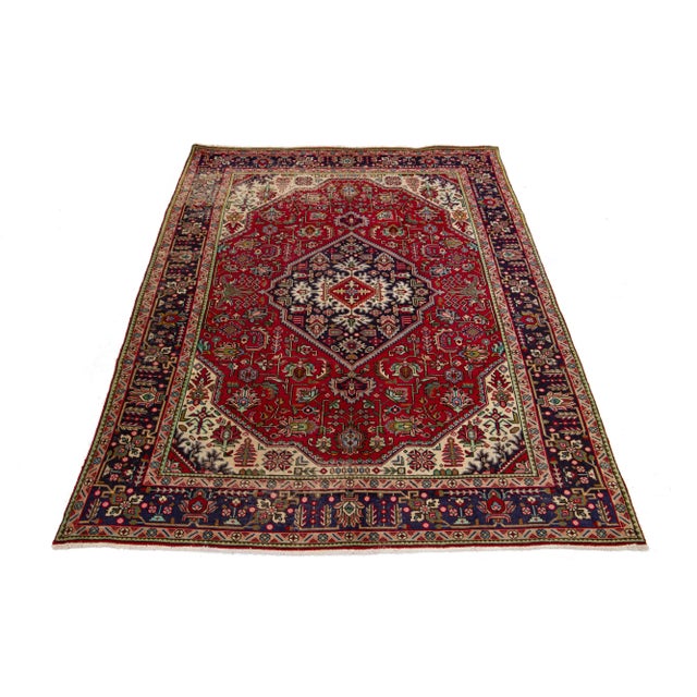 This beautiful Persian Tabriz hand-knotted wool rug has a red field with a multicolor center medallion design. This rug...