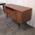 Scandinavian Designs Lanson sideboard in solid poplar with a light walnut stain, black tapered legs, and solid brass foot...