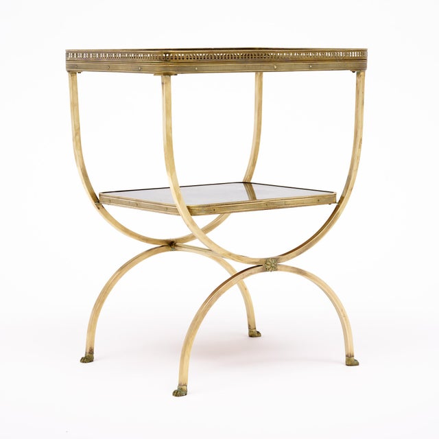 Side table from the Art Deco period in France made of brass with an antiqued mirrored top and antiqued mirrored shelf. The...