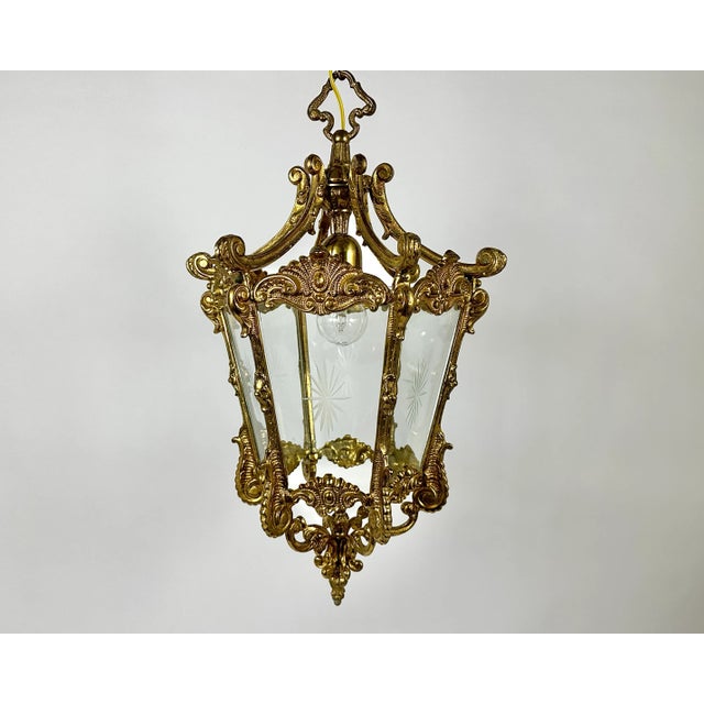 Antique gilded bronze hall lantern with one lamp surrounded by sectional convex tapering glass panels and held within a...