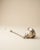 Elegant vintage candle snuffer featuring a long metal shaft, a sculpted bell-shaped snuffer head, and a segmented white...