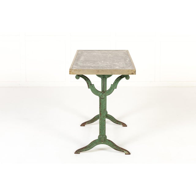 A decorative pair of 19th century cast iron bistro or café tables, retaining their original green painted surface and...