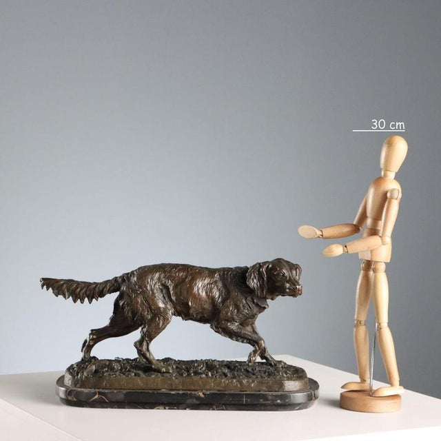 Bronze sculpture on a black marble base depicting a pointing hunting dog. The artist's signature is engraved on the base....