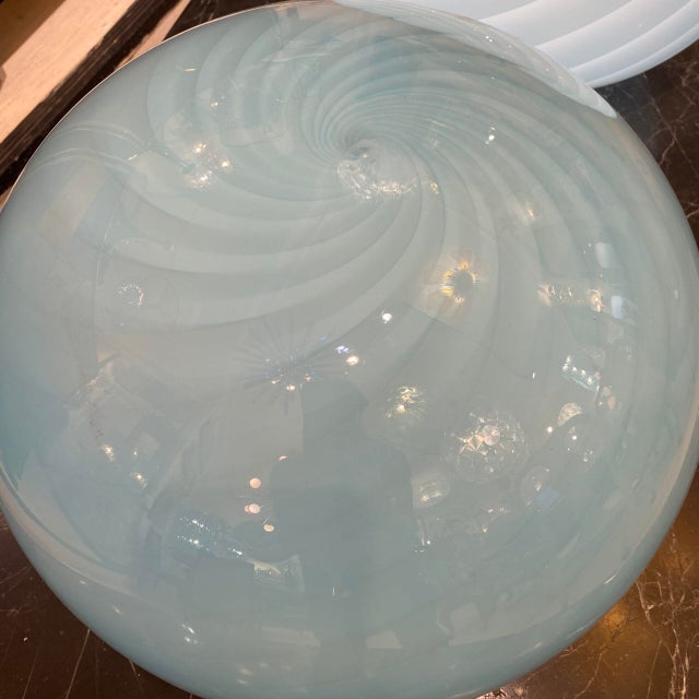 Hand-blown Murano glass lamp in an ovoid shape and baby blue color. The glass creates a spiral effect around the entire...