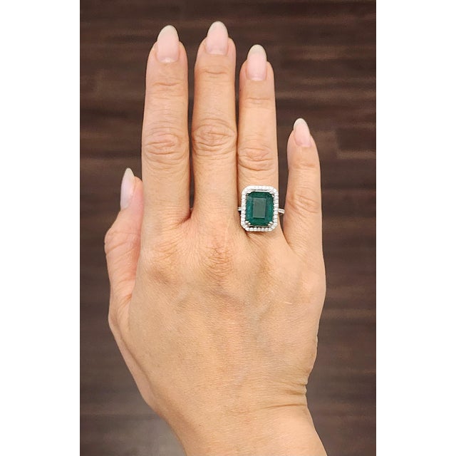 An exquisite 8.59-carat emerald-cut emerald ring, surrounded by a halo of 48 round white diamonds, radiates elegance and...