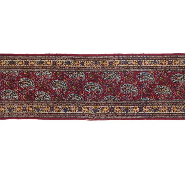 The wine red field is covered by a unidirectional pattern of smooth, rounded off-white botehs, with a small flower and...