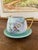 This vintage creamer and saucer set features a delicate hand-painted floral motif in soft pastel tones. The creamer has a...