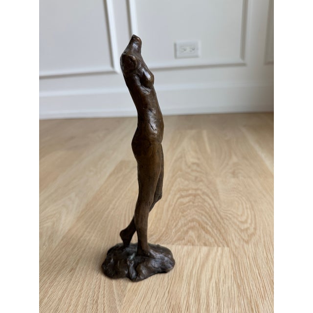 An elegant bronze female figure by American sculptor Tom Corbin (b. 1954), signed and numbered 36/40. The sculpture pairs...