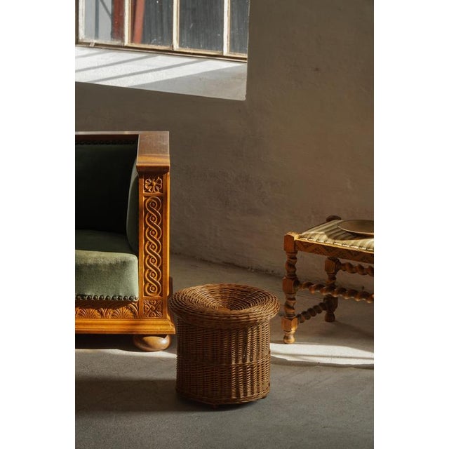 A versatile handcrafted piece in woven rattan, featuring a cylindrical base with a gently recessed, wider top. This design...