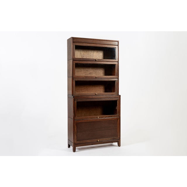This tall antique English mission style five-stack wooden lawyer or barrister bookcase cabinet is from the early 1900s....