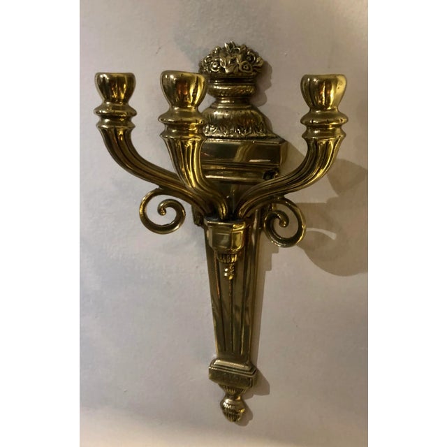 A pair of three-arm elegant neoclassical brass sconces with floral motifs.