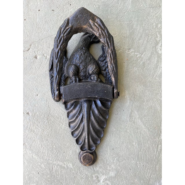 This striking antique door knocker is crafted in solid cast iron and features a bold American eagle perched above a shield...
