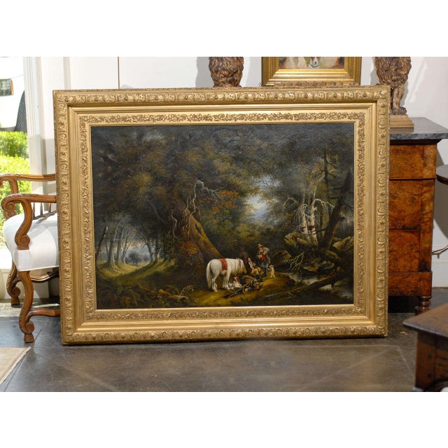 A large horizontal oil on canvas painting with gilded frame featuring men, horses and dogs painted in the style of Alvan...