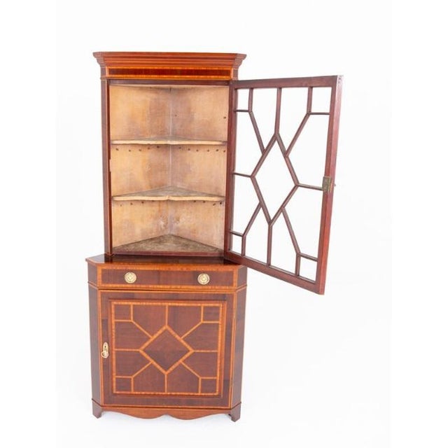 Elegant Sheraton Revival mahogany inlaid corner cabinet Raised on graceful splay feet with shaped apron Finely figured...