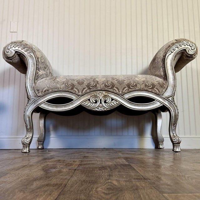Stunning vintage bench featuring an ornate Rococo Revival design with dramatic scroll arms, cabriole legs, and carved...
