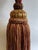 This large, decorative tassel is mounted on a metal stand. The tassel is burgundy and gold and features decorative...