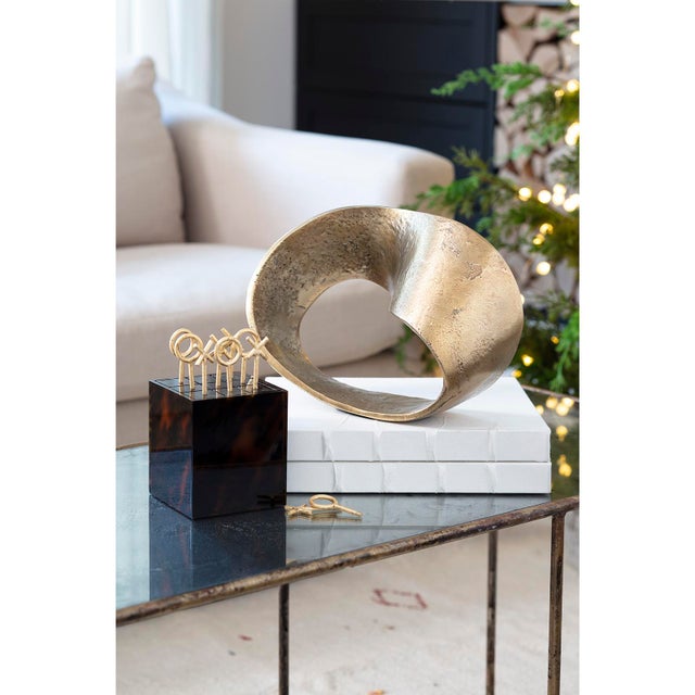 An infinity knot was crafted out of aluminum and cast to capture a textured surface. This object is an industrial work of...