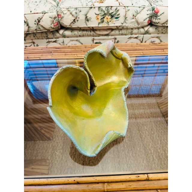 An expressive hand-built pottery sculpture featuring an organic, free-form silhouette with flowing, undulating edges....