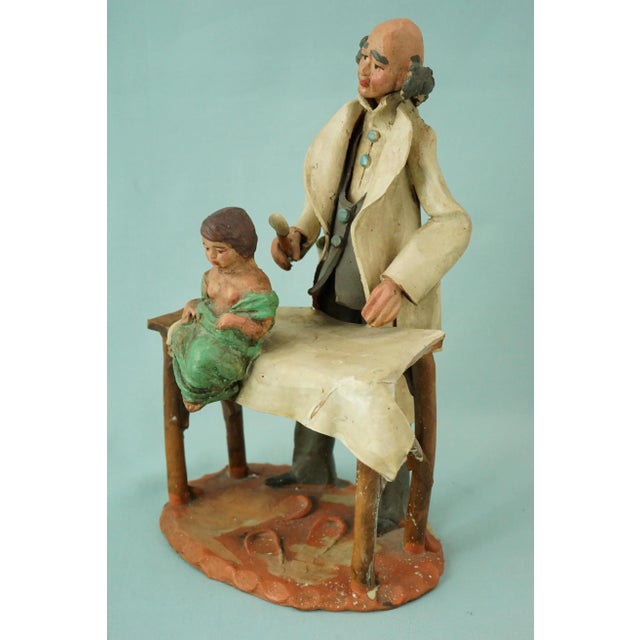 A wonderful, rare, entirely hand-molded terracotta sculpture, a unique piece depicting a pediatrician examining a child on...
