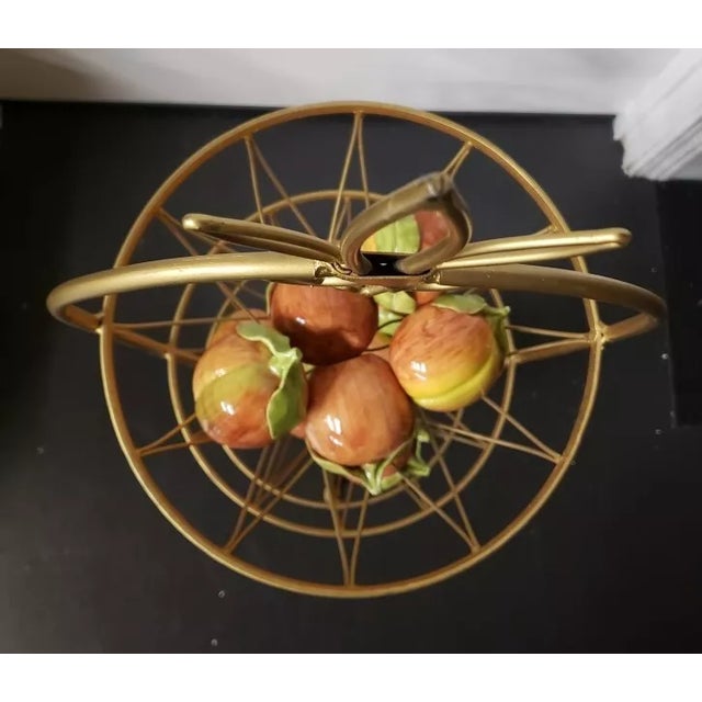 This is a 1970s Hollywood Regency Gilt Metal 3 Tier Fruit Basket with Italian Ceramic Apples. The basket measures 37" high...