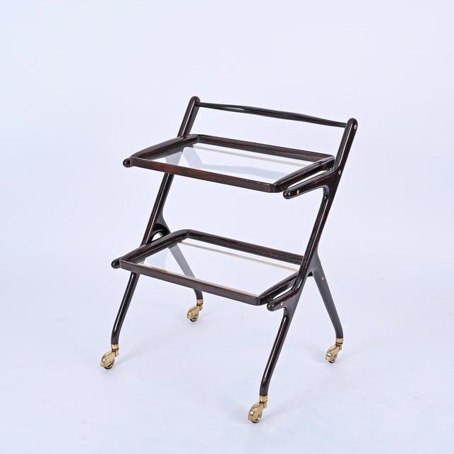 Gorgeous midcentury bar cart in wood and brass with two removable crystal glass trays. This wonderful object designed by...