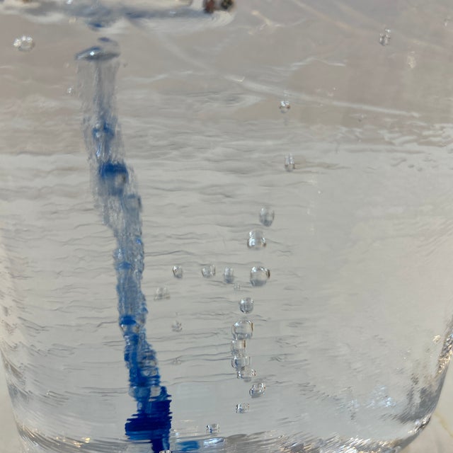 Thick transparent textured glass candle holder with blue placed inside during the blowing and molding process. It...