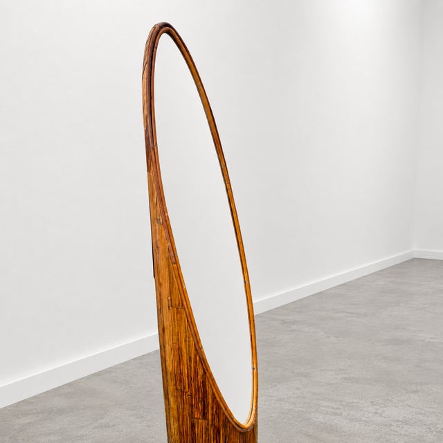 Vintage sculptural floor mirror made from bamboo and pencil reed rattan with a warm amber-brown finish. The tall, slender...