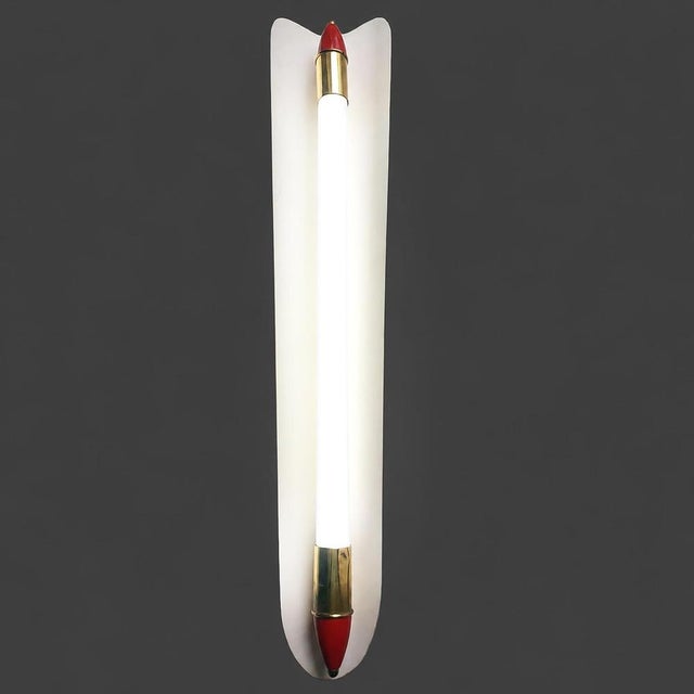 Original mid-century wall light sconce. It consists of a long, narrow, white-lacquered asymmetrical reflector that is...