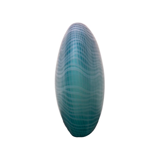 The vessel features an elegant opaline teal/turquoise base overlaid with an intricate, flowing grid or web pattern in...