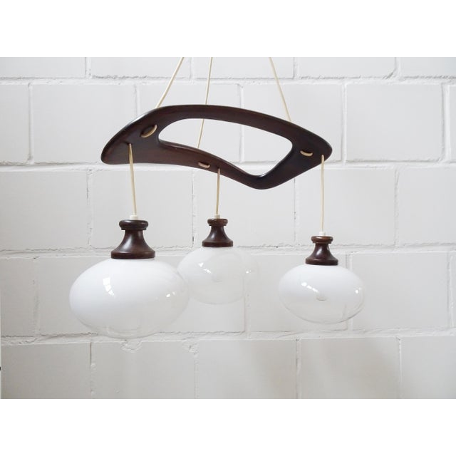 Italian hanging lamp by Mazzega from the 1970s. Beautifully shaped Mid-Century design made of arched wood and and three...