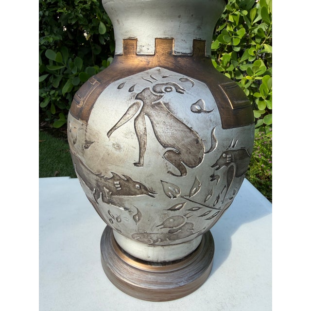 Vintage sculptural table lamp featuring raised animal relief decoration and a warm bronze-tone finish. The vessel-form...