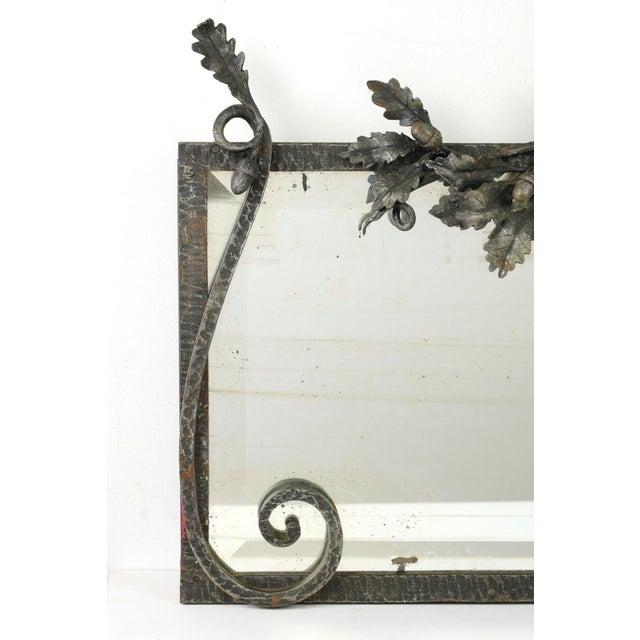 French Art Deco mirror with a hand wrought iron frame decorated with a metal branch of leaves and acorns. The mirror has...