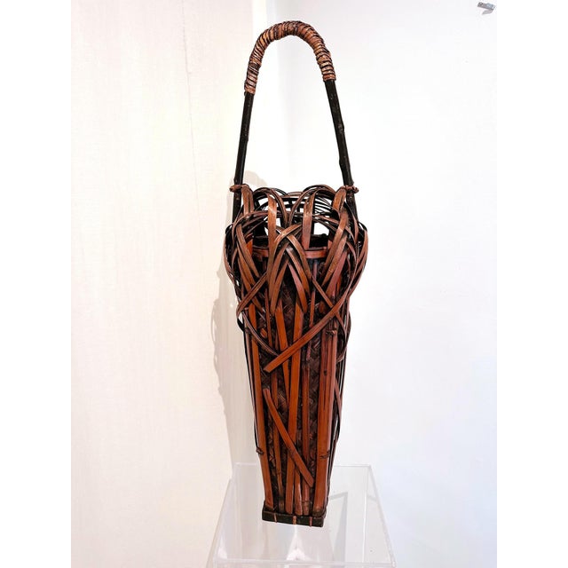A very tall and elegant Japanese Ikebana flower arrangement basket handwoven with sooted bamboo and rattan circa 1900-20s...