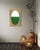 A deep forest green oval sits low and grounded within this composition, its color rich enough to nearly read as black in...