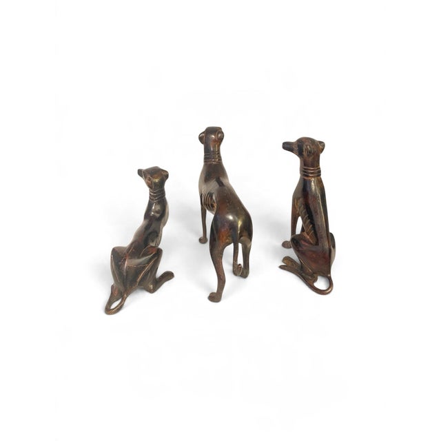 A striking and rare complete three-piece set of mid-20th-century English sighthound figurines, expertly styled in the...