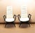 A pair of high-back lounge chairs featuring dark lacquered wooden frames with graceful curved legs and arms, paired with...