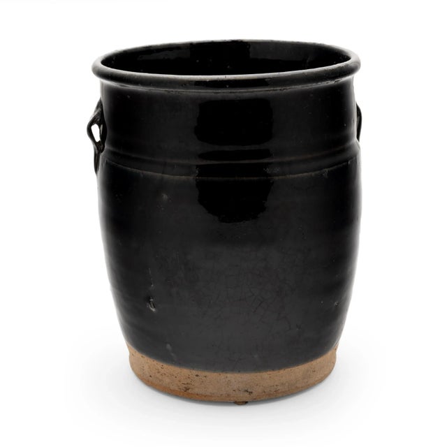 A thick black glaze softly covers the tapered form of this early 20th-century jar, once used daily in a Qing-dynasty...