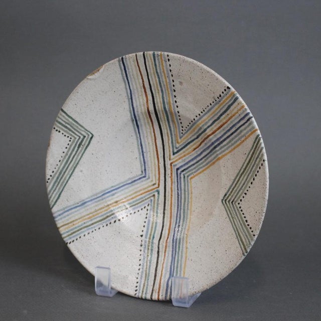 A charming ceramic bowl by Bruno Gambone, decorated with a bold geometric composition of radiating striped chevrons in...