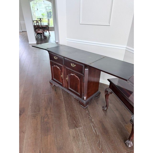 A fine dark mahogany drop-leaf buffet in the Chippendale tradition. Features two brass-handled drawers, two cabinet doors,...