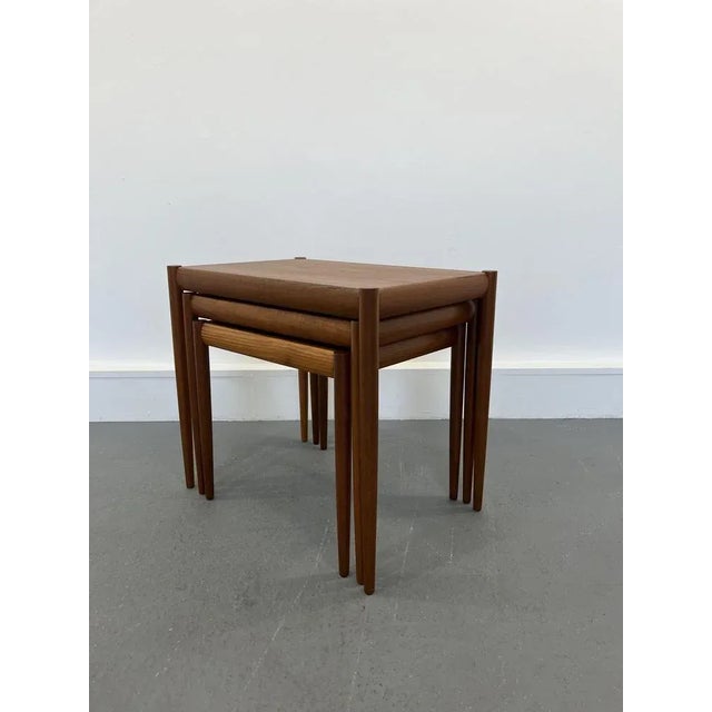 Set of three nesting tables in teak manufactured in Denmark in the 1960s. The tapered legs joining the top of the table...