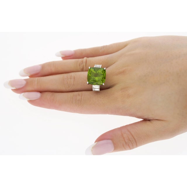 14.11 Carat Cushion Cut Green Peridot and Baguette Cut Diamond Side Stone Ring in 18K White Gold. This sophisticated ring...