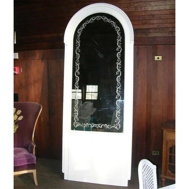 French Boiserie panel containing an arched mirror with vine and ribbon motif etching.